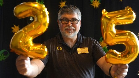 Ken Kato holds gold balloons that spell 25