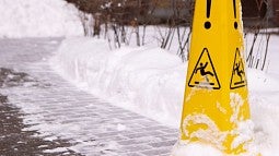 Yellow hazard cone on snow-covered sidewalk