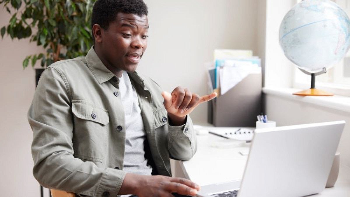 Black man at desk using American Sign Language
