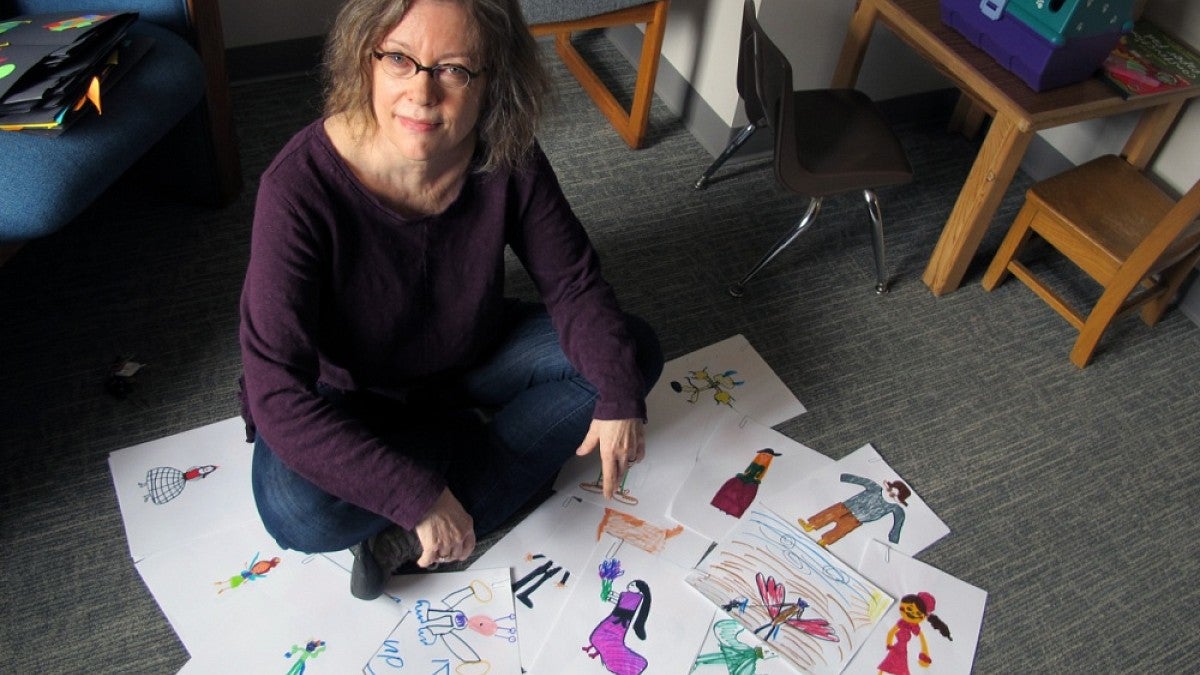 Marjorie Taylor sits amid creative drawings done by 8- to 10-year-old children