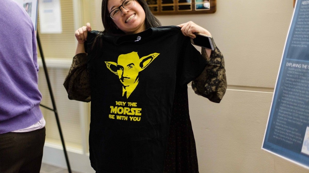 Student holding t-shirt with slogan 'May the Morse be with you."
