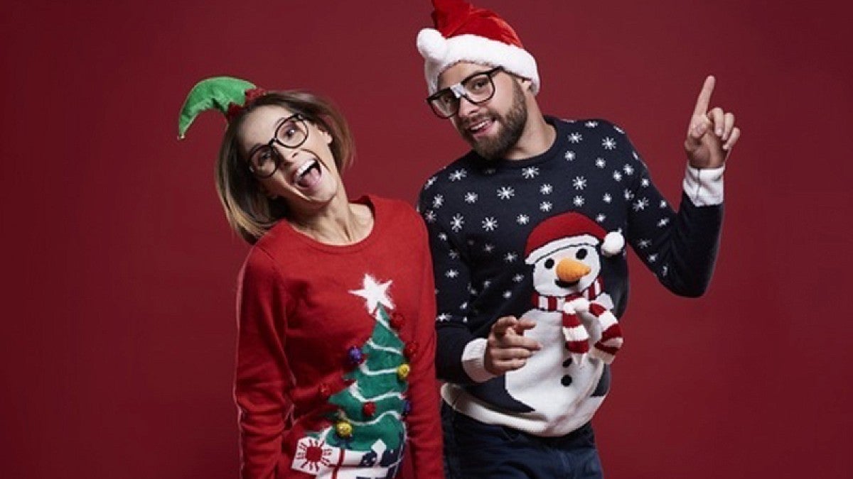 Image shows two people wearing their seasonal ugly sweaters