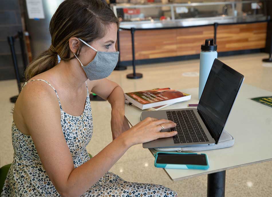 A student sitting at a table working on her laptop computer