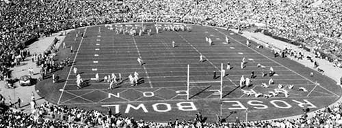 Black and white photo of football players warming up on the field, and the crowded stands prior to the start of the 1958 Rose Bowl game between the University of Oregon and Ohio State