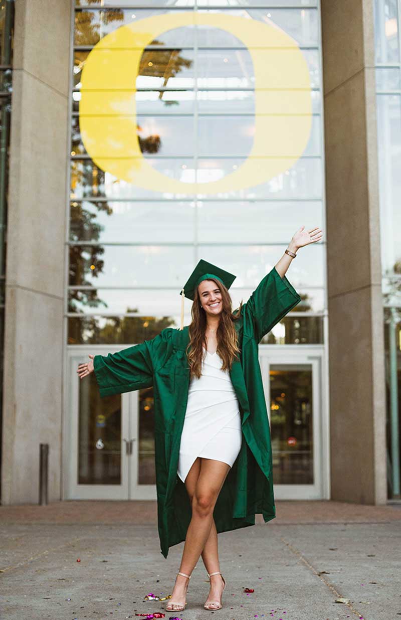 Sabrina Ionescu in her cap and gown in front of the O on the Lillis Business Complex