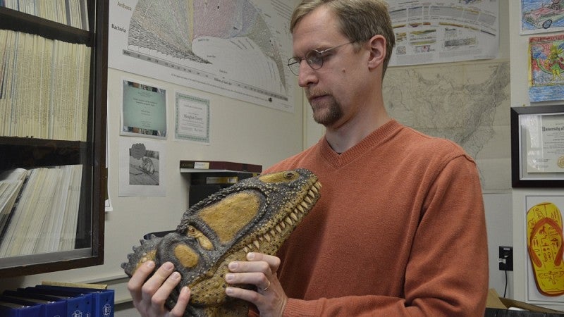 Edward Davis holding a dinosaur mock-up