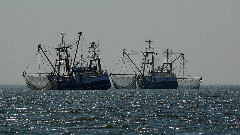 image shows two commercial fishing trawlers side by side in the ocean