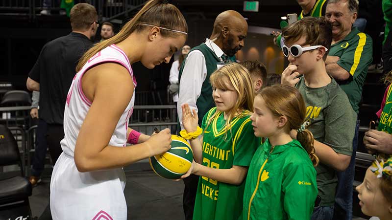 Sabrina Ionescu signing a basketball for young Oregon fans