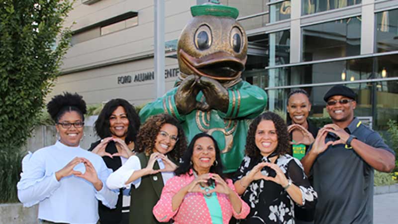 Members of the Black Alumni Network throwing the O next to a statue of the Duck throwing the O