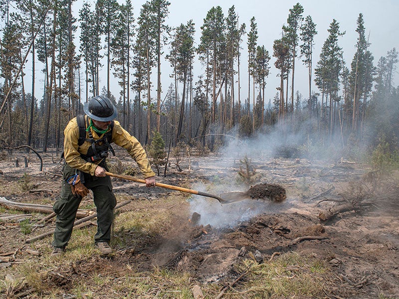 Firefighter shoveling dirt onto a fire at the Oregon Bootleg fire in 2021