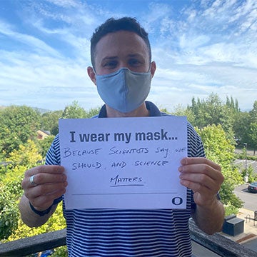 David Markowitz wearing a mask with a sign that says I wear a mask because scientists say we should. And science matters.