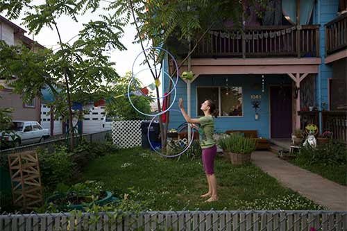 A woman juggling hula-hoops in her yard