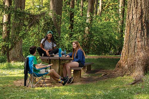 Students sitting together at a picnic table in the outdoors
