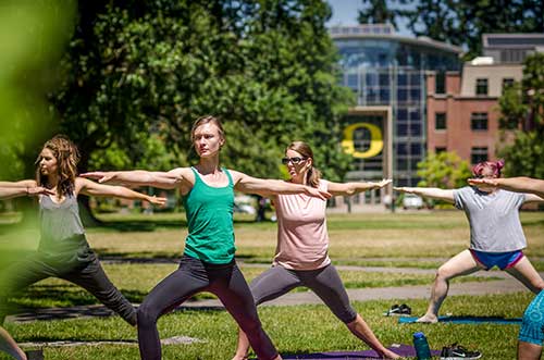 Students doing yoga on the Memorial Quad in front of the Lillis Business Complex