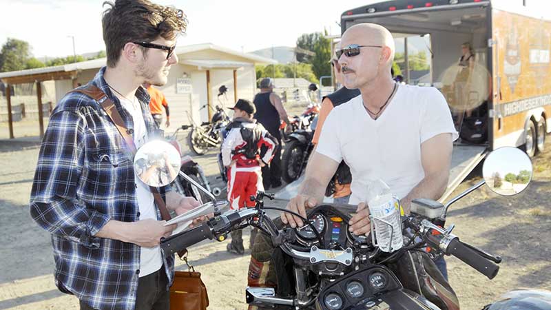 Isaac Gibson interviewing a man near a motorcycle