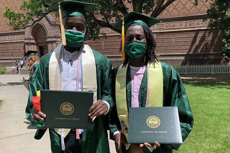 2021 UO Grads holding diplomas in front of the JSMA