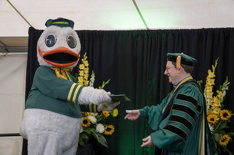 The Duck handing President Schill a diploma at the UO 2021 graduation ceremony