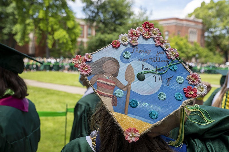 A graduation cap reading &quot;There's just no telling how far I'll go&quot; with an illustration of 'Moana' and a wave