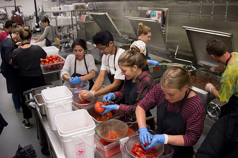 Students in the Carson Dining kitchen turning the tomatoes into pizza sauce