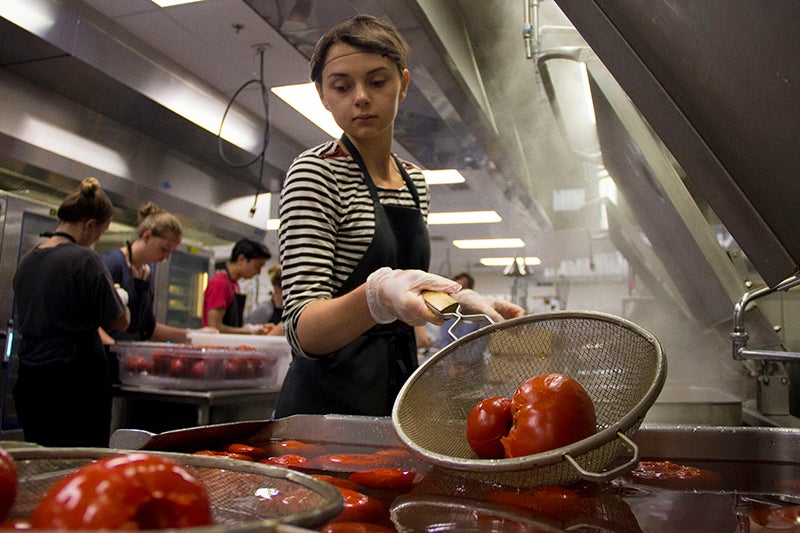 A student blanching tomatoes in hot water