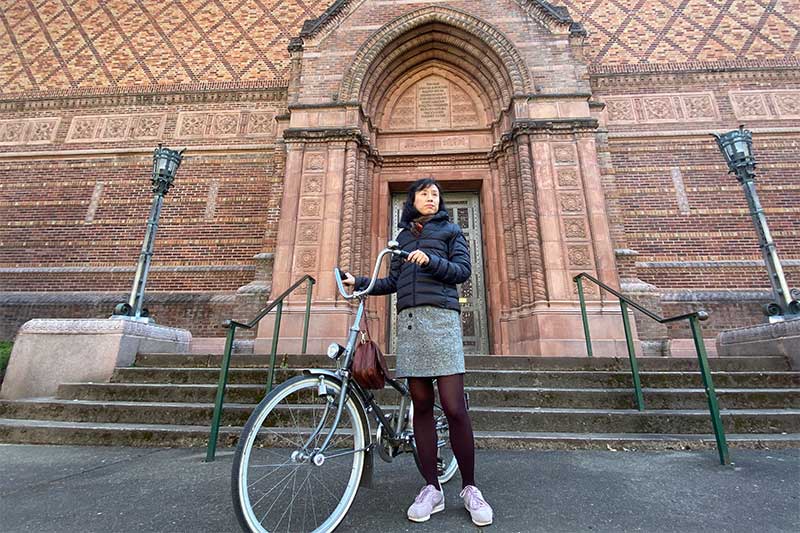 Joyce Cheng with a bicycle outside of the Jordan Schnitzer Museum of Art