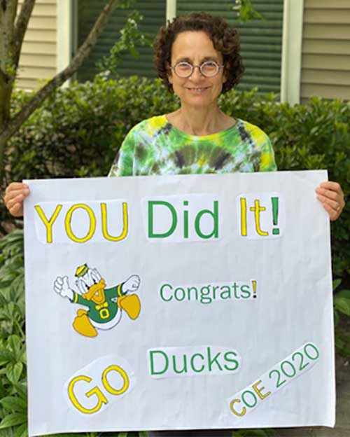 Professor Nancy Golden with a sign that says You Did It! Congrats! Go Ducks! COE 2020