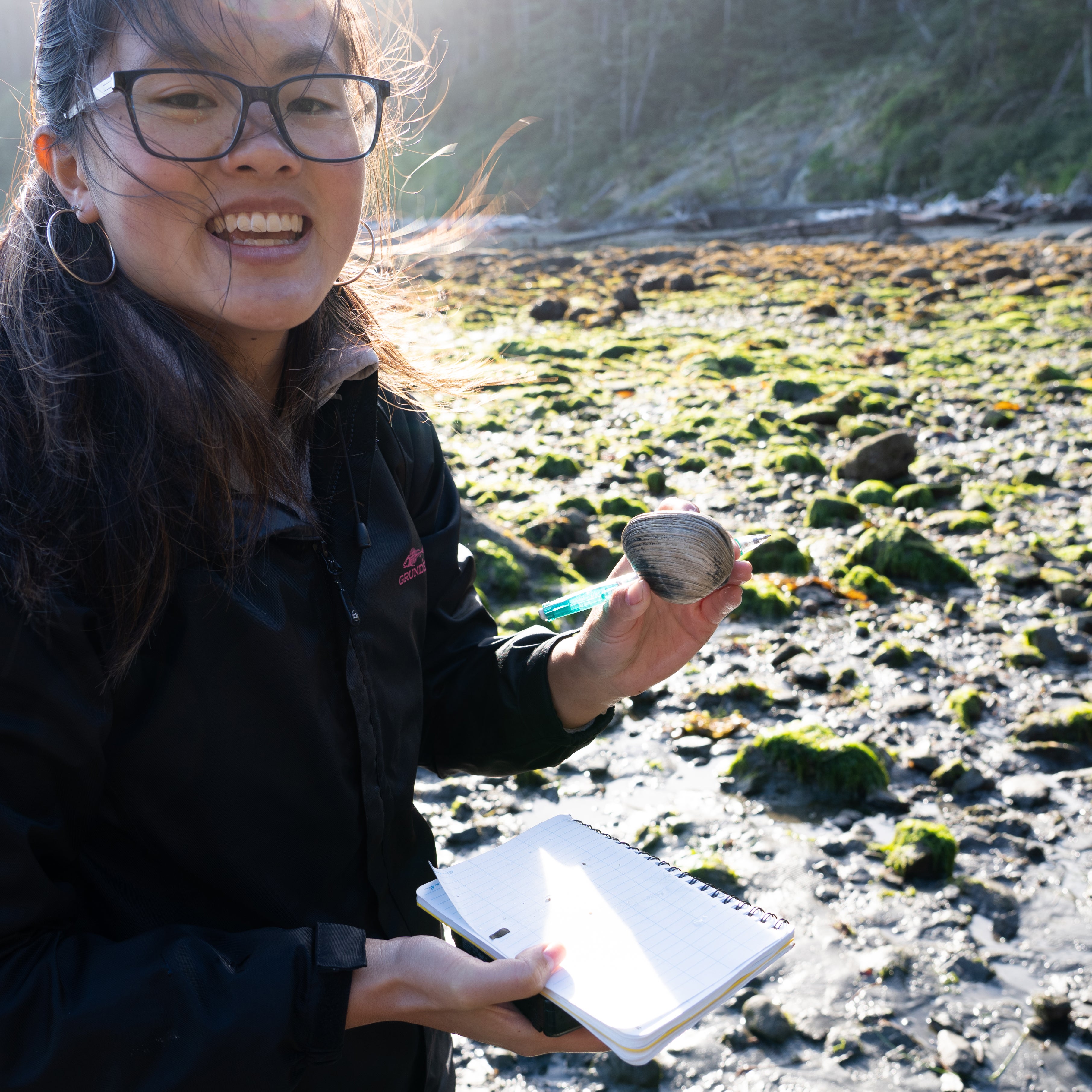 Young woman holding a notebook and a bivalve mollusk.