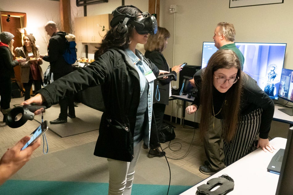 Andrea McFarlane (right) assists a student with a virtual reality experience during an event