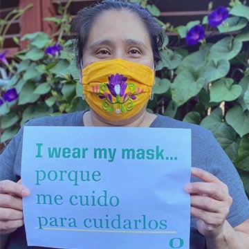 Rosa Chavez wearing a mask with a sign that says I wear a mask porque me cuido para cuidarlos.