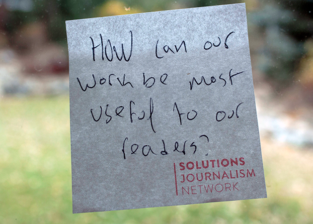 a sticky note on a window reads &quot;how can our work be most useful to our readers?&quot;