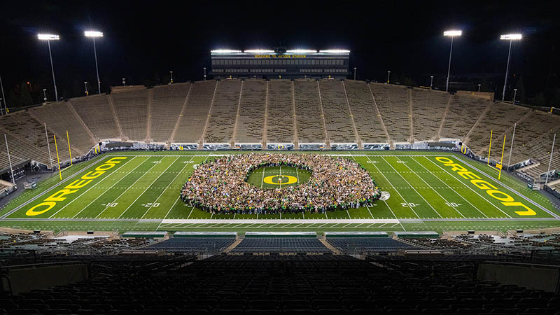 Class of 2025 standing on the field of Autzen Stadium in the shape of an &quot;O&quot;