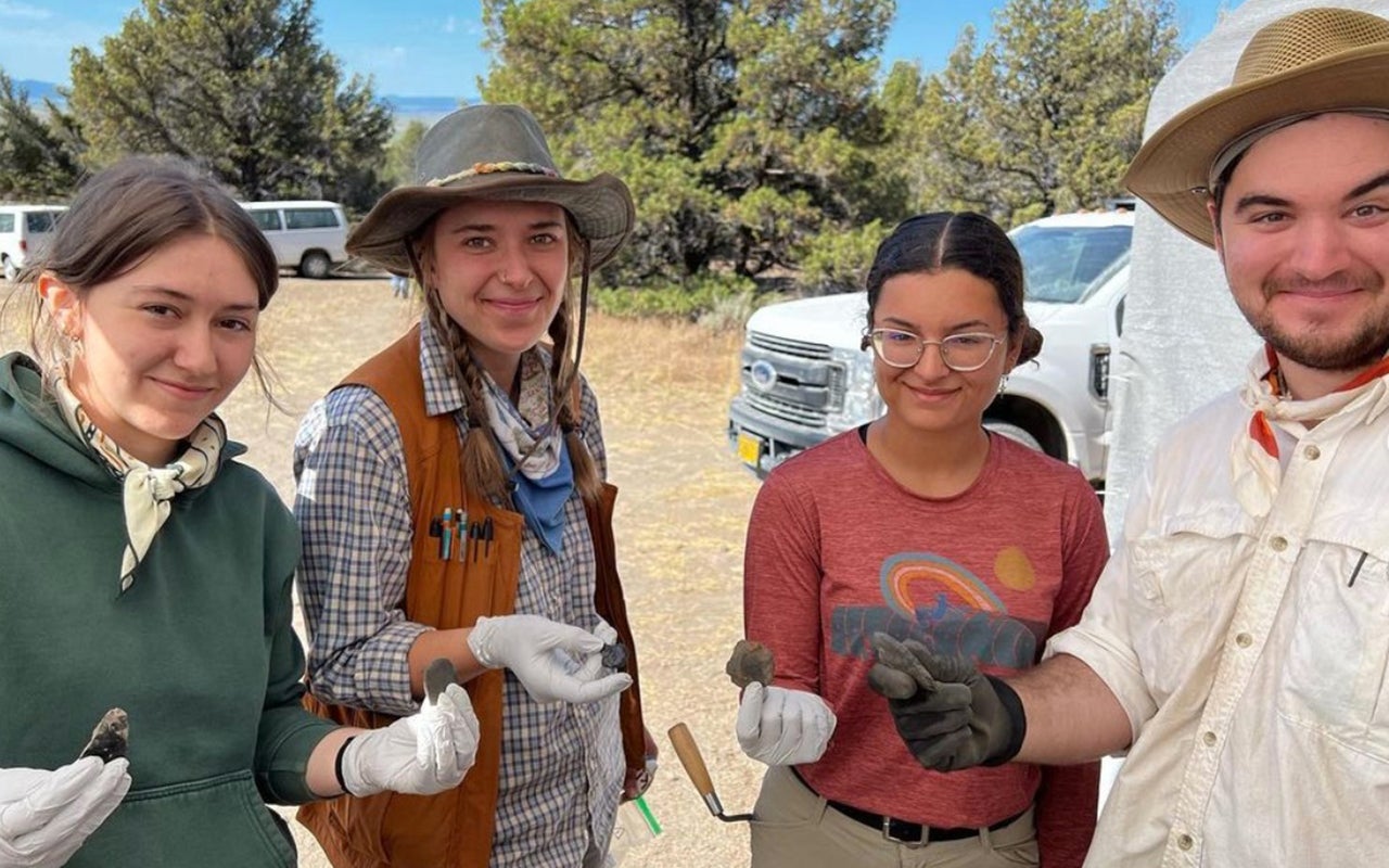 Four young people in digging outfits proudly hold out rocks with man-made edges.