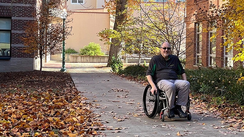 John Miller navigating campus in wheelchair