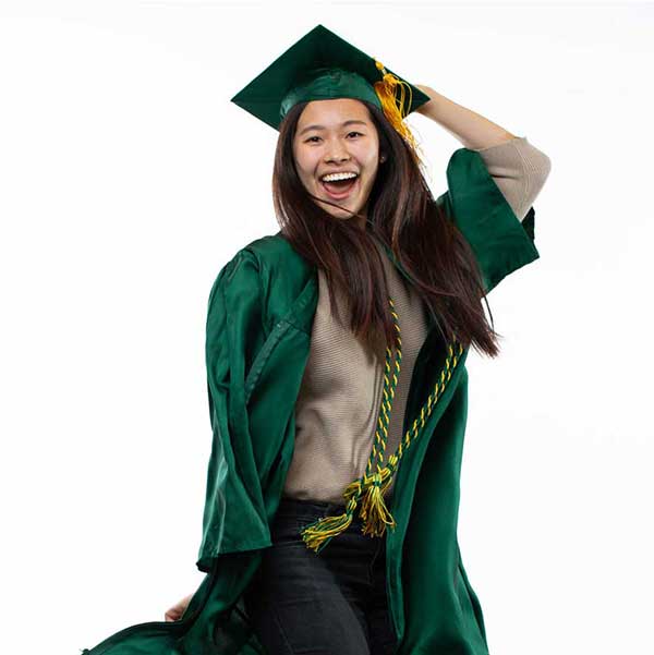 Kahei Lee in her cap and gown jumping in the air