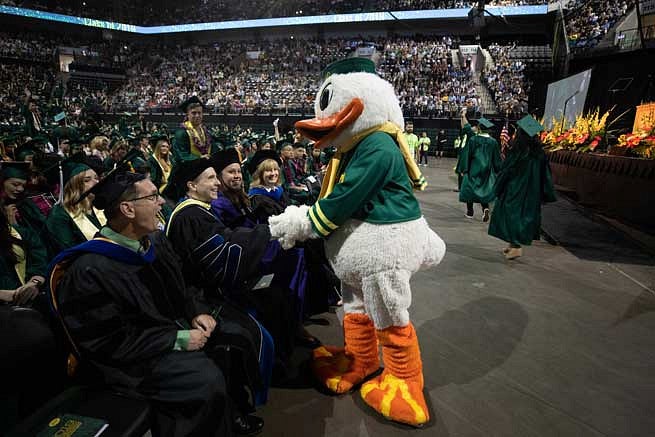 The Duck shaking hands with graduates in Matthew Knight Arena