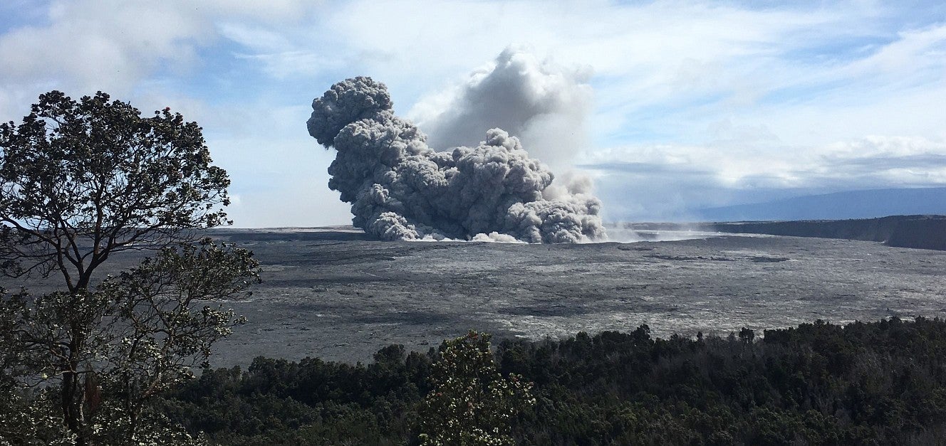 A cloud of smoke pours out of a caldera