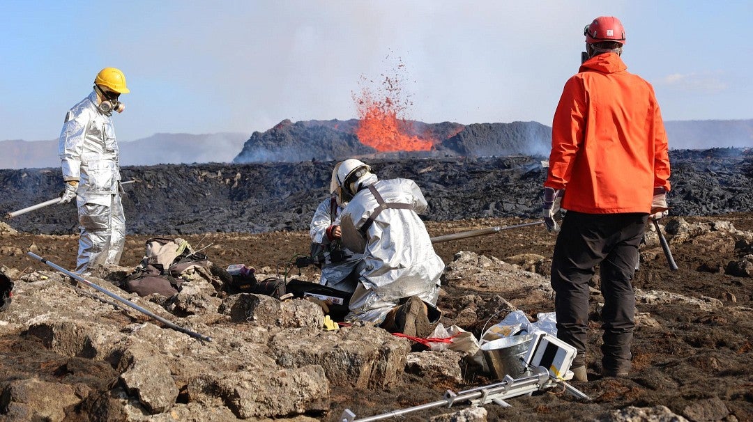 Scientists check equipment near an active volcano eruption