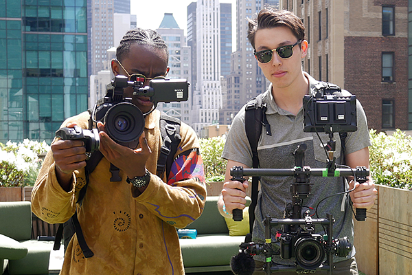 two students hold camera equipment