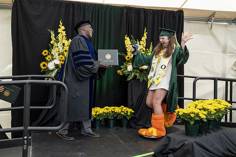2021 UO grad wearing duck feet getting diploma on stage