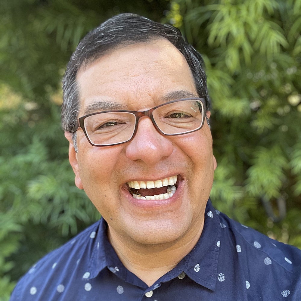 Man with big smile, wearing glasses.