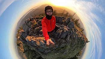 Jasper Zhou standing at the top of Spencer Butte with a fish eye lense