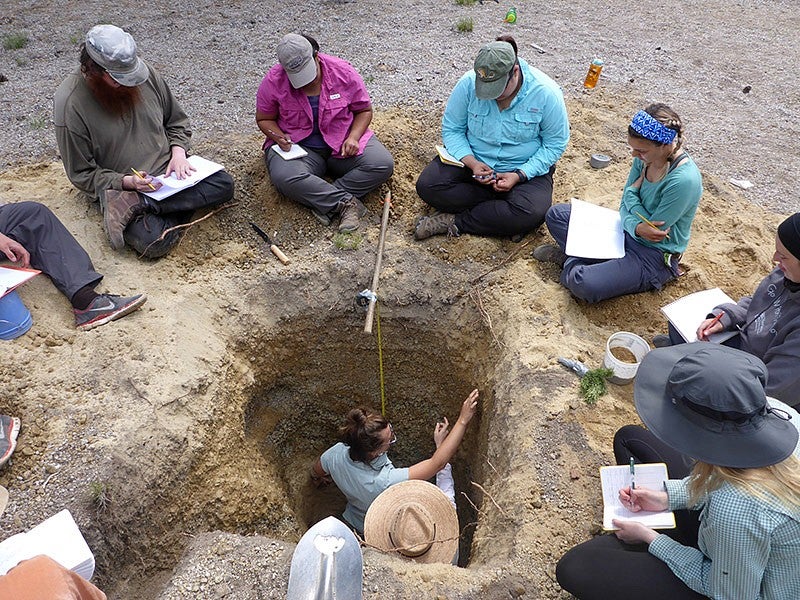 Students at June 2019 field camp work around pit at Newberry volcano