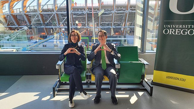 President Michael Schill and Governor Kate Brown throwing the O while sitting in the seats that will be in Hayward Field overlooking Hayward Field construction