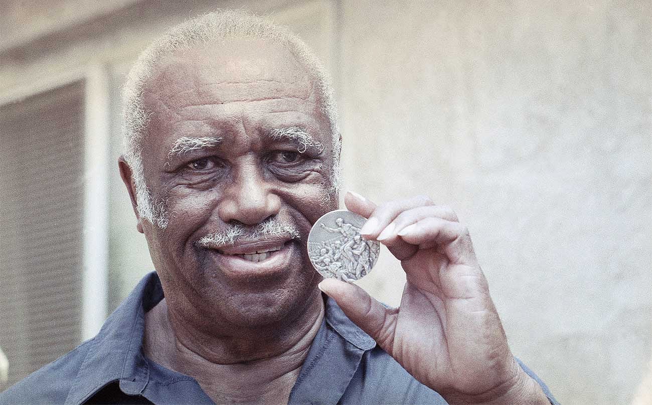 An older Mack Robinson holding up his silver medal from the 1936 Berlin Olympics
