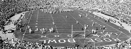 Black and white photo of football players warming up on the field, and the crowded stands prior to the start of the 1958 Rose Bowl game between the University of Oregon and Ohio State