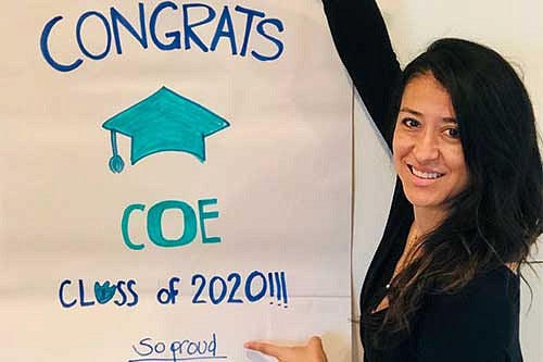 Professor Ruby Batz Herrera with a sign that says Congrats COE Class of 2020. So proud.