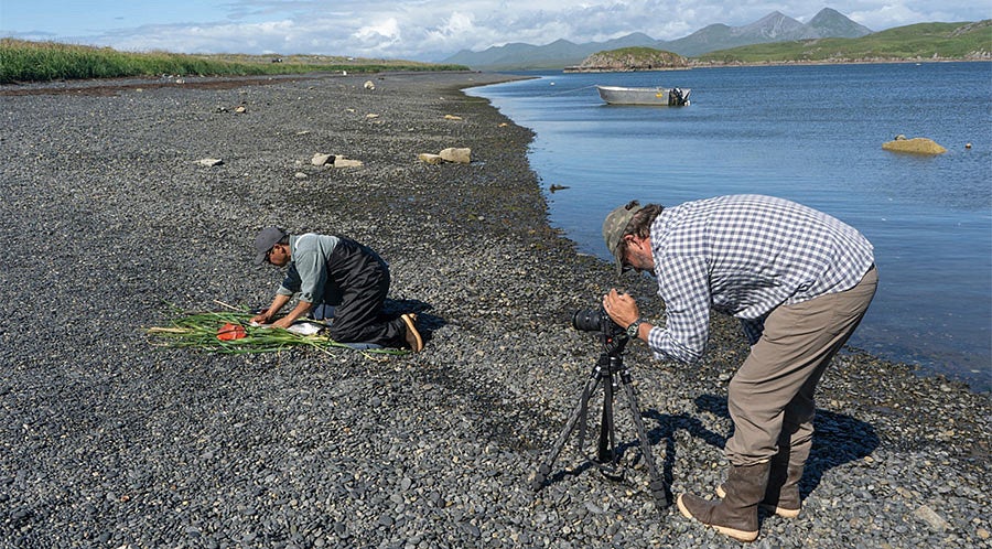 Mark Blaine films Sven Haakanson as he fillets a salmon for the documentary series “A Kayak to Carry Us.”