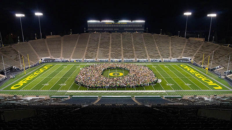Class of 2025 standing on the field of Autzen Stadium in the shape of an "O"