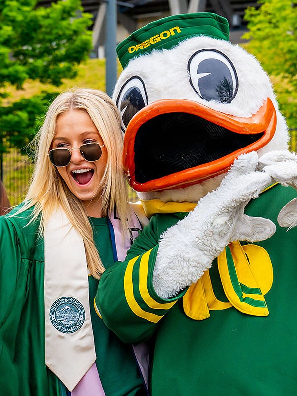 Student taking a selfie with the Duck at the 2022 UO graduation at Autzen Stadium