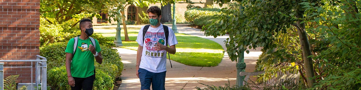 Two students walking through campus wearing masks